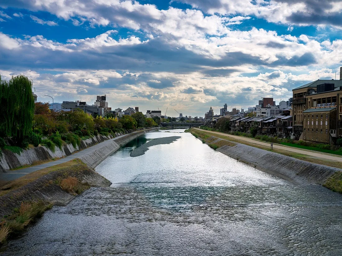 The calm Kamogawa riverbank in Kyoto under a blue sky