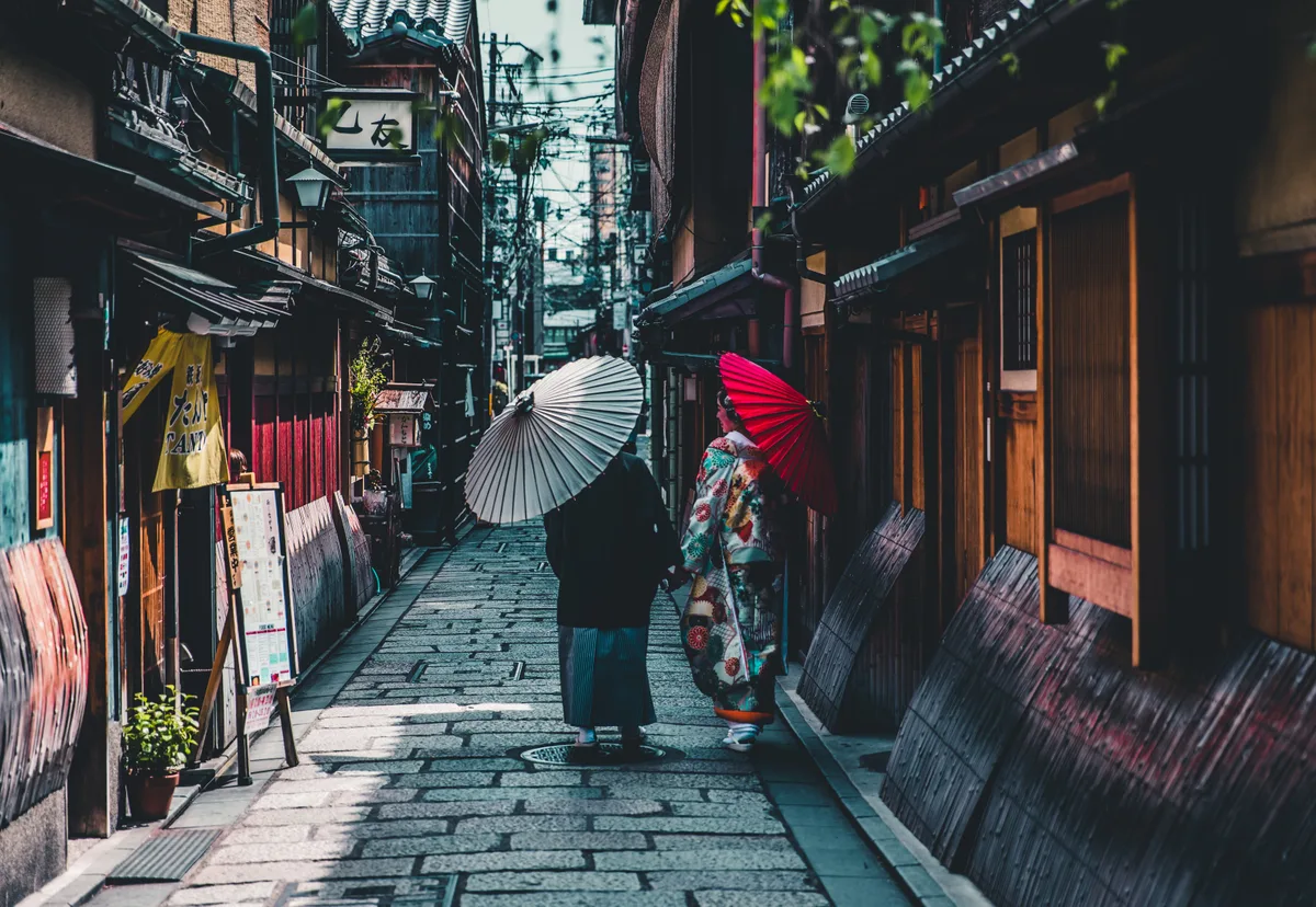 Walking a cobbled Gion lane in Kyoto in kimono with a Japanese umbrella